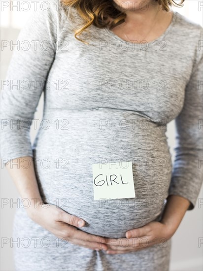 Portrait of smiling pregnant woman with adhesive note on belly