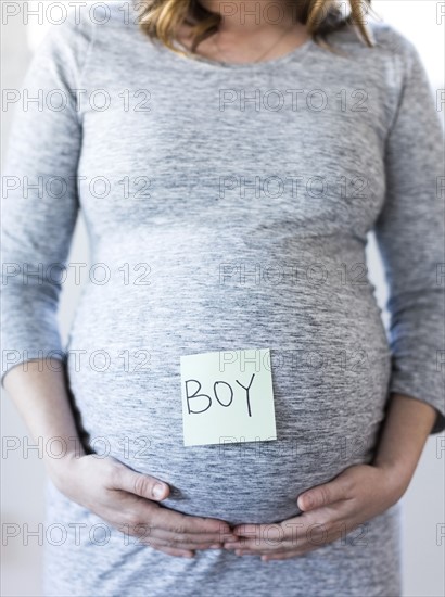 Portrait of smiling pregnant woman with adhesive note on belly