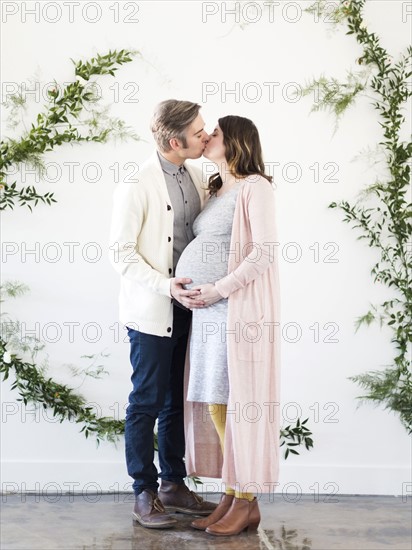 Portrait of men and  pregnant woman kissing