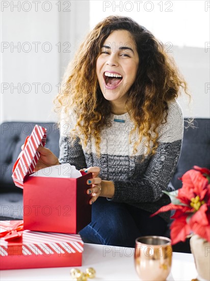 Happy woman on sofa opening Christmas gift