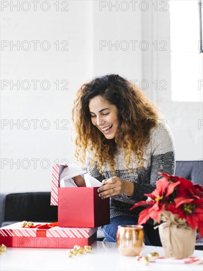 Happy woman on sofa opening Christmas gift