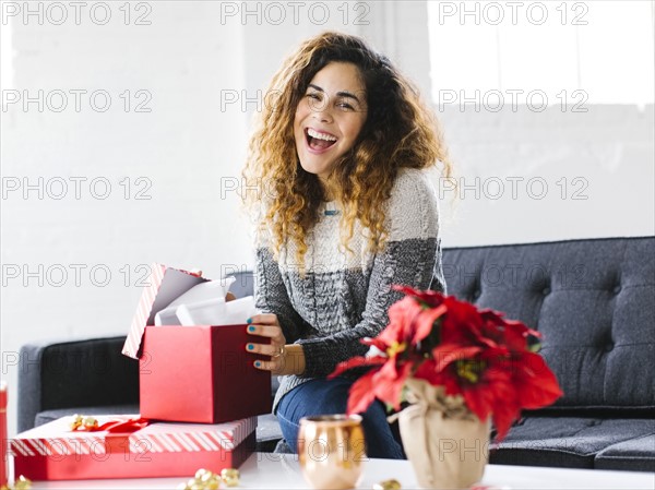 Happy woman on sofa opening Christmas gift