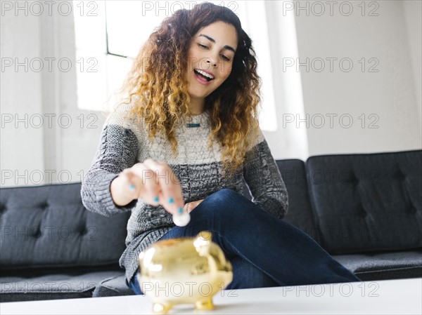 Woman dropping coin into gold piggy bank