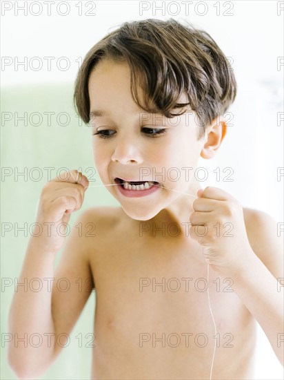 Boy (6-7) flossing teeth