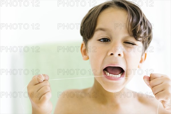 Boy (6-7) flossing teeth