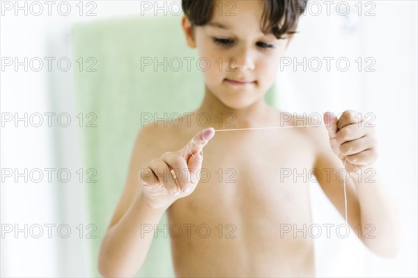 Boy (6-7) flossing teeth