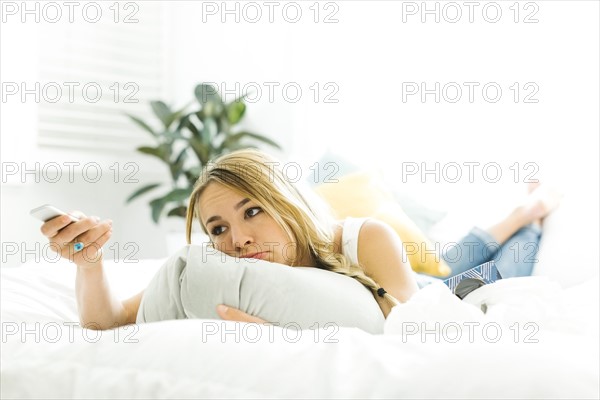 Woman in bed with tv remote