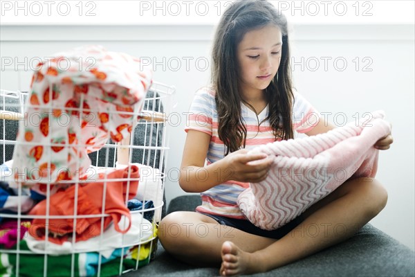 Girl (10-11) folding laundry