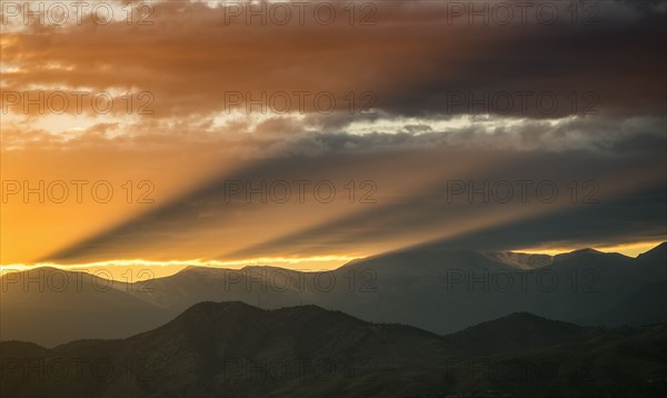 USA, Colorado, Denver, Setting sun shining through clouds over Front Range