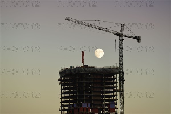 USA, Colorado, Denver, Full moon in background of skyscraper construction site at dusk