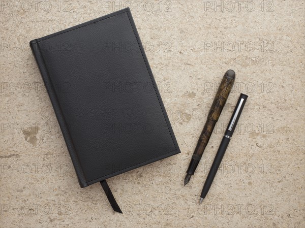 Studio shot of black notebook and two pens