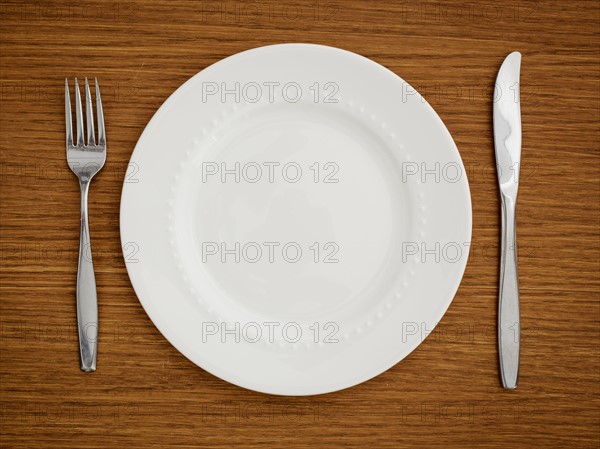 Studio shot of white plate with fork and knife