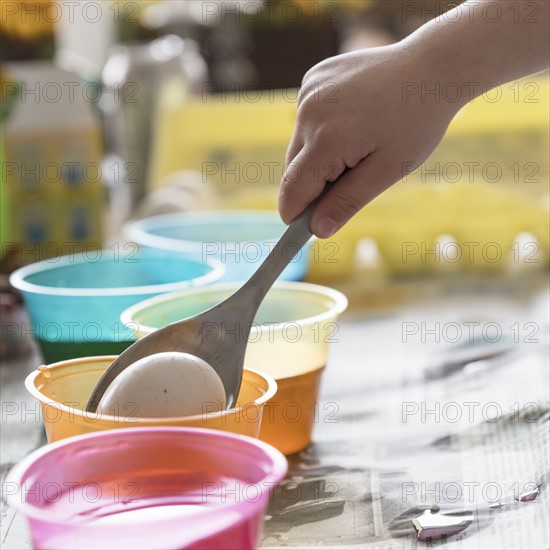 Girl (4-5) making colored Easter eggs