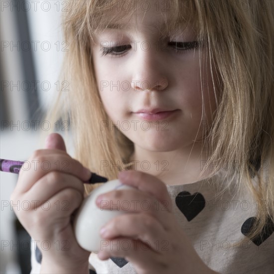 Girl (4-5) making colored Easter eggs