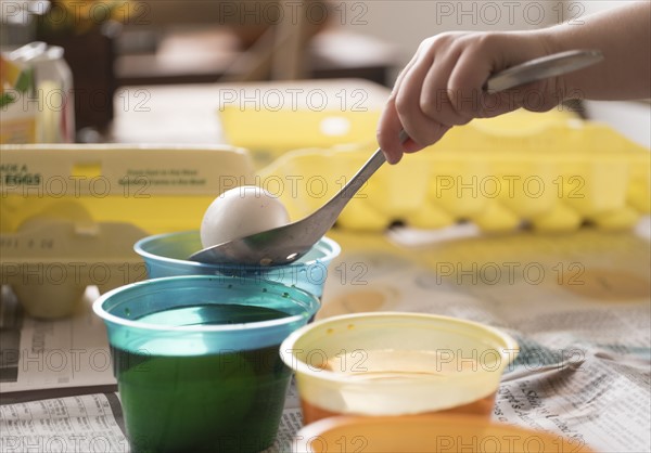 Girl (4-5) making colored Easter eggs