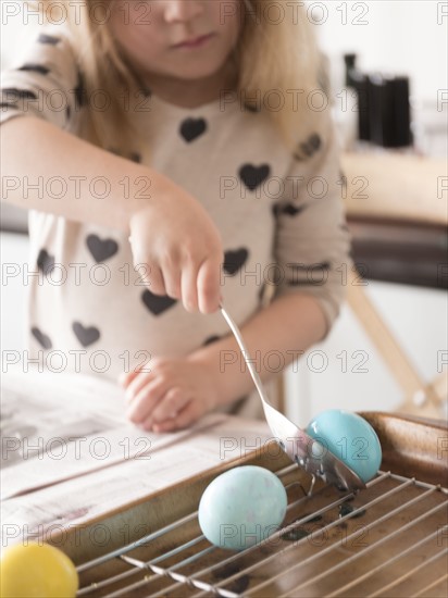 Girl (4-5) making colored Easter eggs