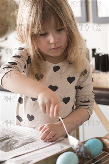 Girl (4-5) making colored Easter eggs