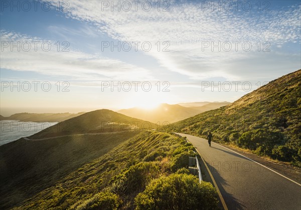 USA, California, San Francisco, California, Man walking on coastline road at sunset