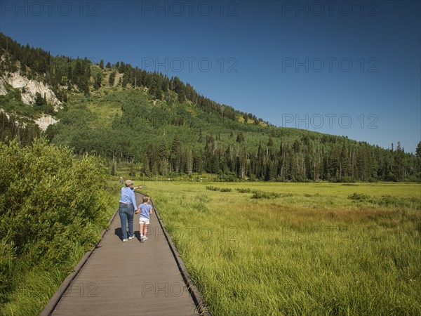 USA, Utah, Lake City, Girl (4-5) with grandmother walking on boardwalk through wetland