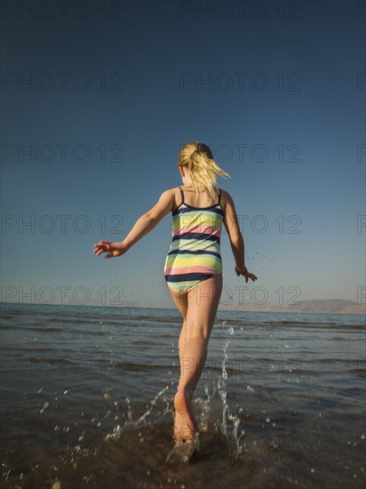 Girl (4-5) running into lake