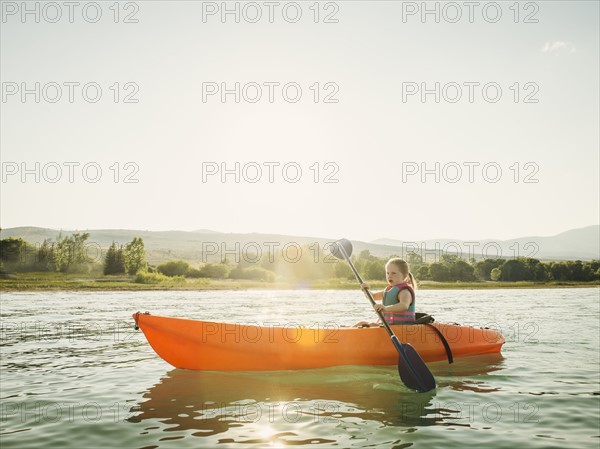 Girl (4-5) kayaking on lake at sunset