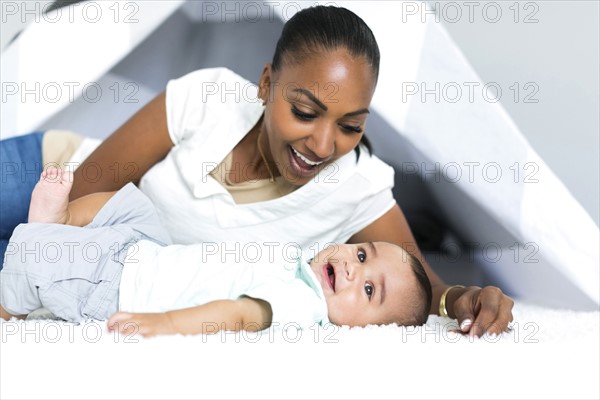 Mother lying down with baby boy (2-5 months) on floor