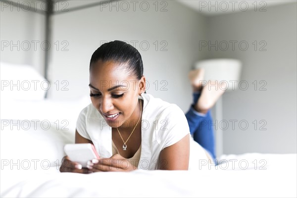 Woman lying on bed and using smart phone