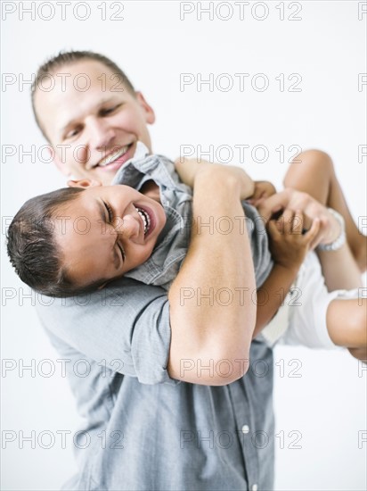 Father holding son (2-3) and laughing