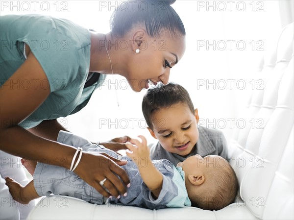 Mother with two sons (2-5 months, 2-3) on sofa