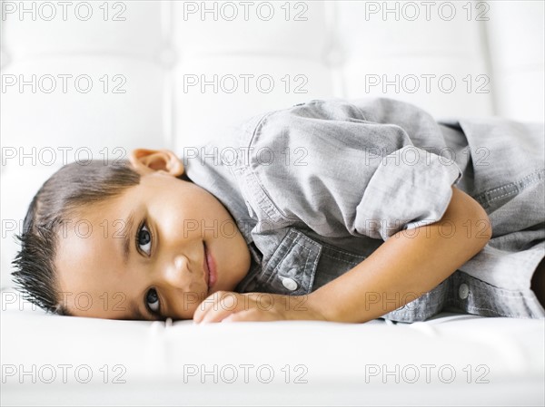 Boy (2-3) lying down on white sofa