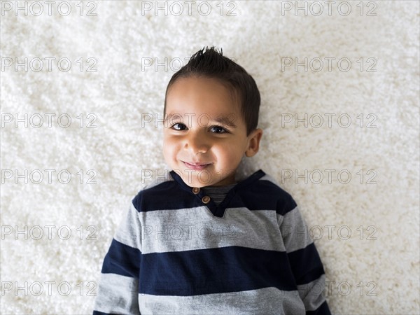 Boy (2-3) lying down on carpet