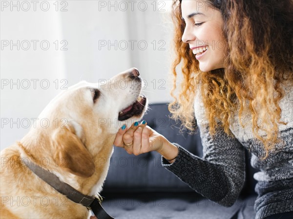 Smiling woman stroking dog in living room