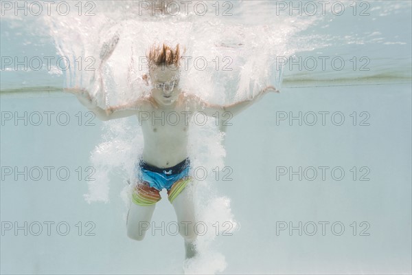 Boy (6-7) jumping into swimming pool