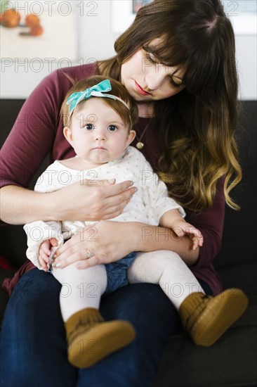 Mother with daughter (12-17 months) sitting on sofa