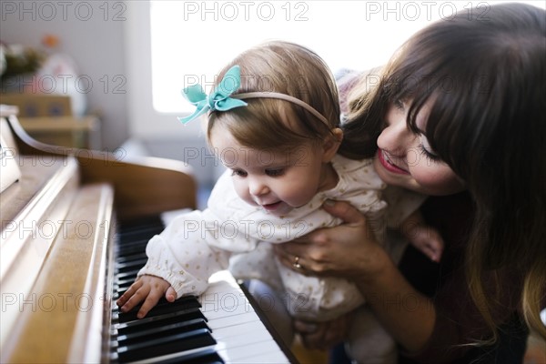 Mother with daughter (12-17 months) playing piano