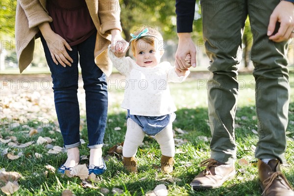 Parents walking with daughter (12-17 months) in park