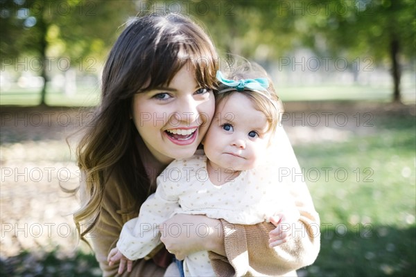 Portrait of mother carrying daughter (12-17 months) in park