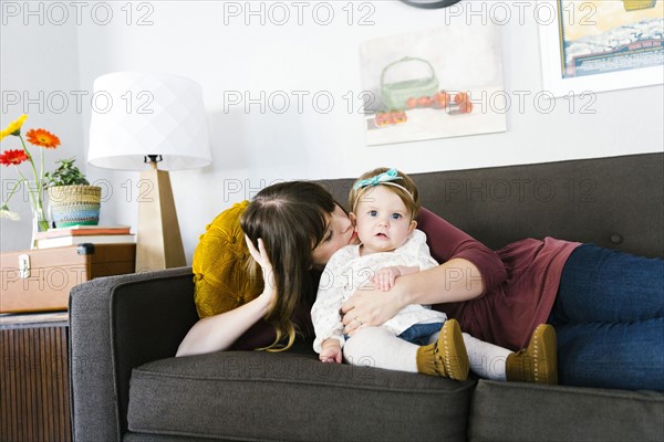 Mother and daughter (12-17 months) on sofa