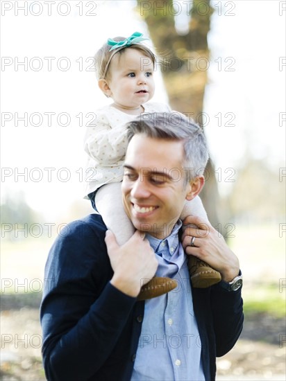 Father carrying daughter (12-17 months) on shoulders