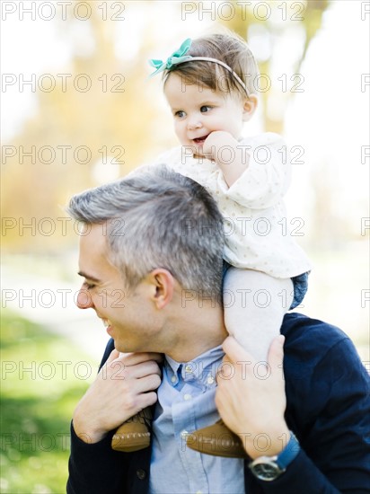 Father carrying daughter (12-17 months) on shoulders