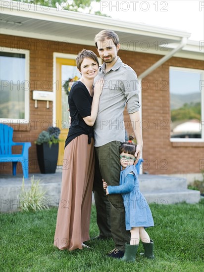 Parents with daughter (2-3) standing in front of house