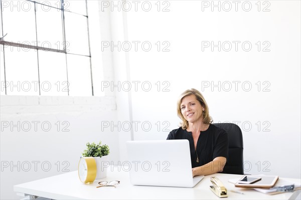 Woman using laptop, looking at camera