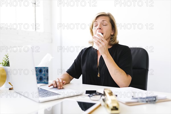 Woman using laptop and sneezing