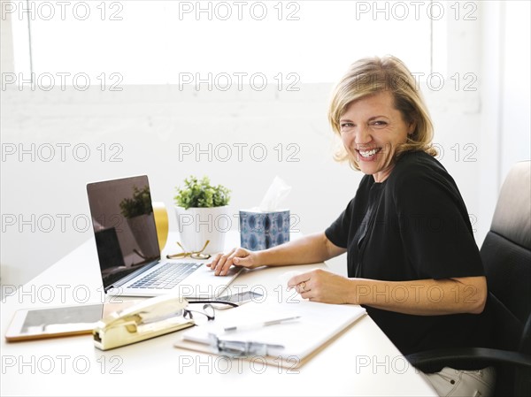 Woman using laptop, looking at camera