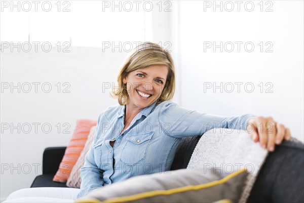 USA, Utah, Salt Lake City, Portrait of happy Mature woman sitting on sofa