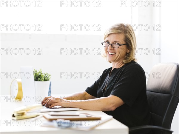 Portrait of Mature woman in office typing on laptop