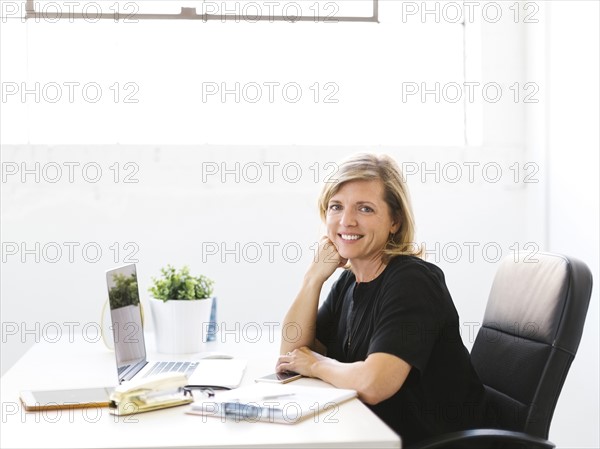 Portrait of Mature woman in office with hand on chin