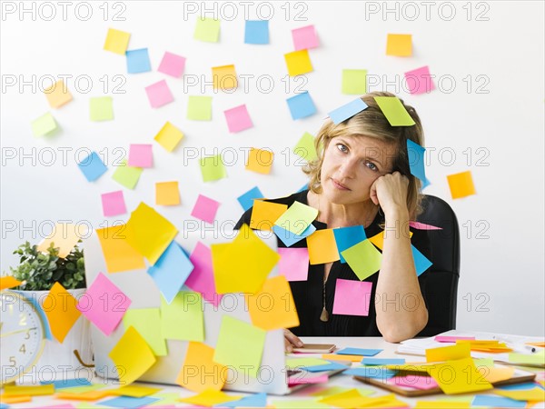 Portrait of Mature woman at office covered with adhesive notes