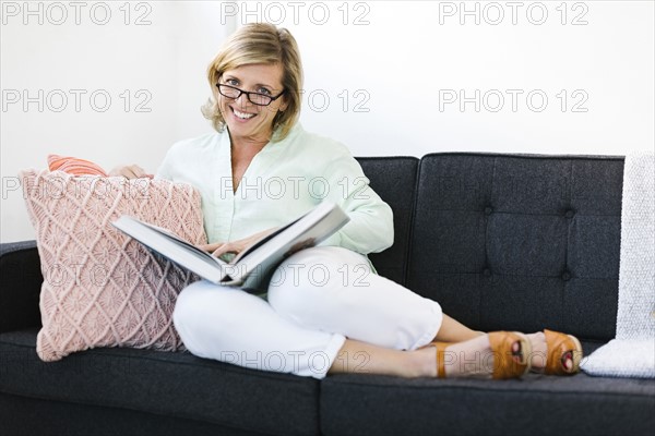 Woman sitting with book on sofa