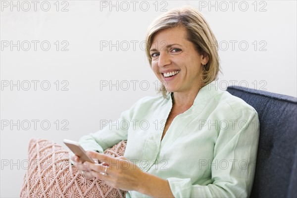 Woman holding smart phone on sofa